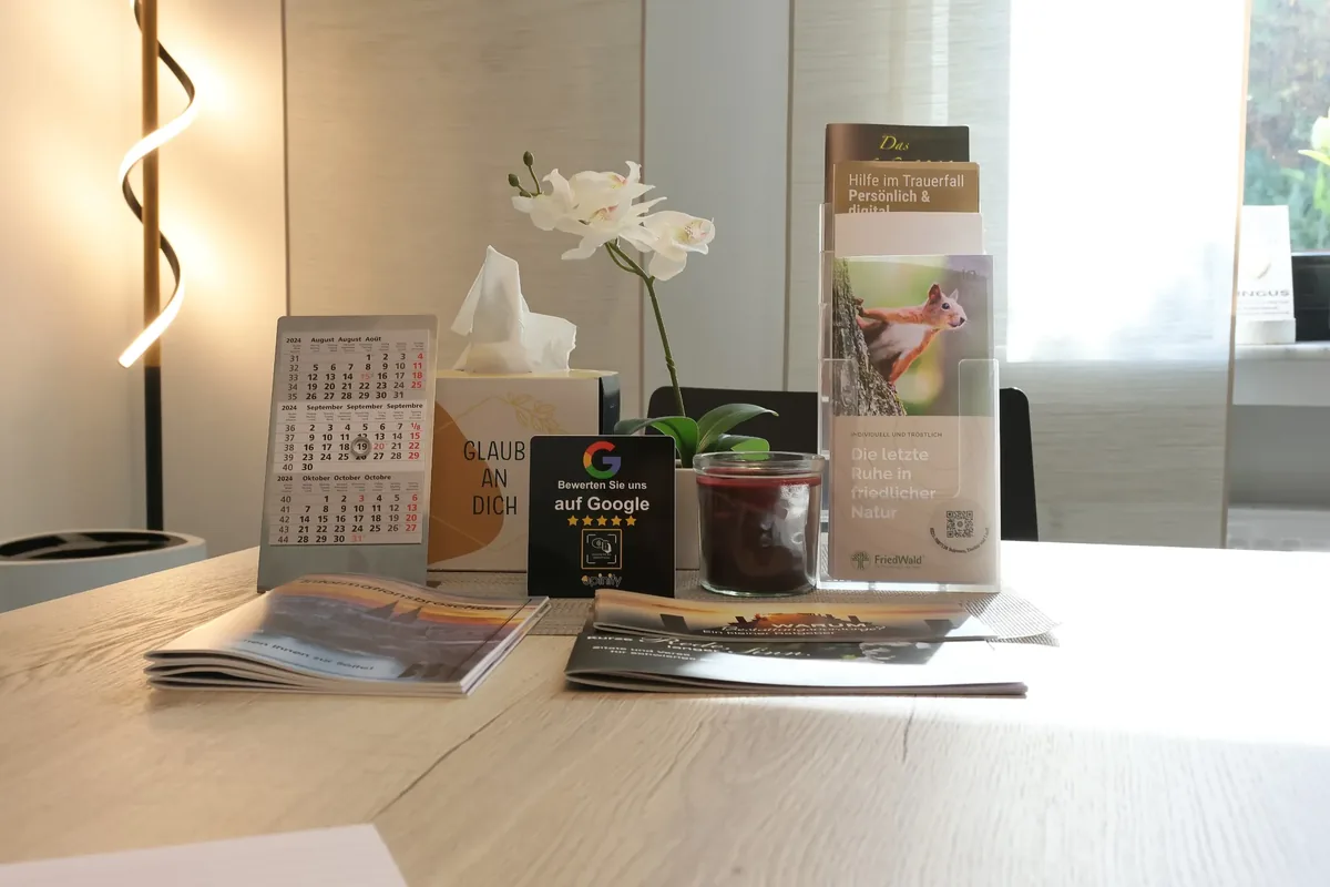 Beratungstisch mit Informationsmaterial, weißer Orchidee und Leuchte