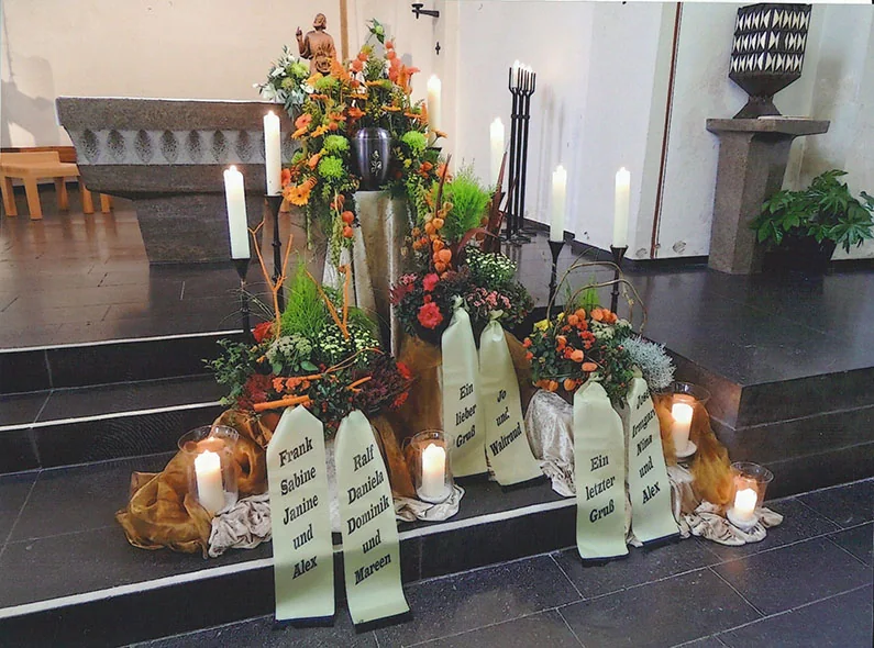 Von Bestattungen Lauff gestaltete Trauerfeier in einer Kirche: Urne auf einer Stele, herbstlicher Blumenschmuck und Kerzen