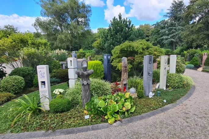 Bestattungsgarten mit aufrechten Grabstelen, Blumen und einem geschwungenen Weg