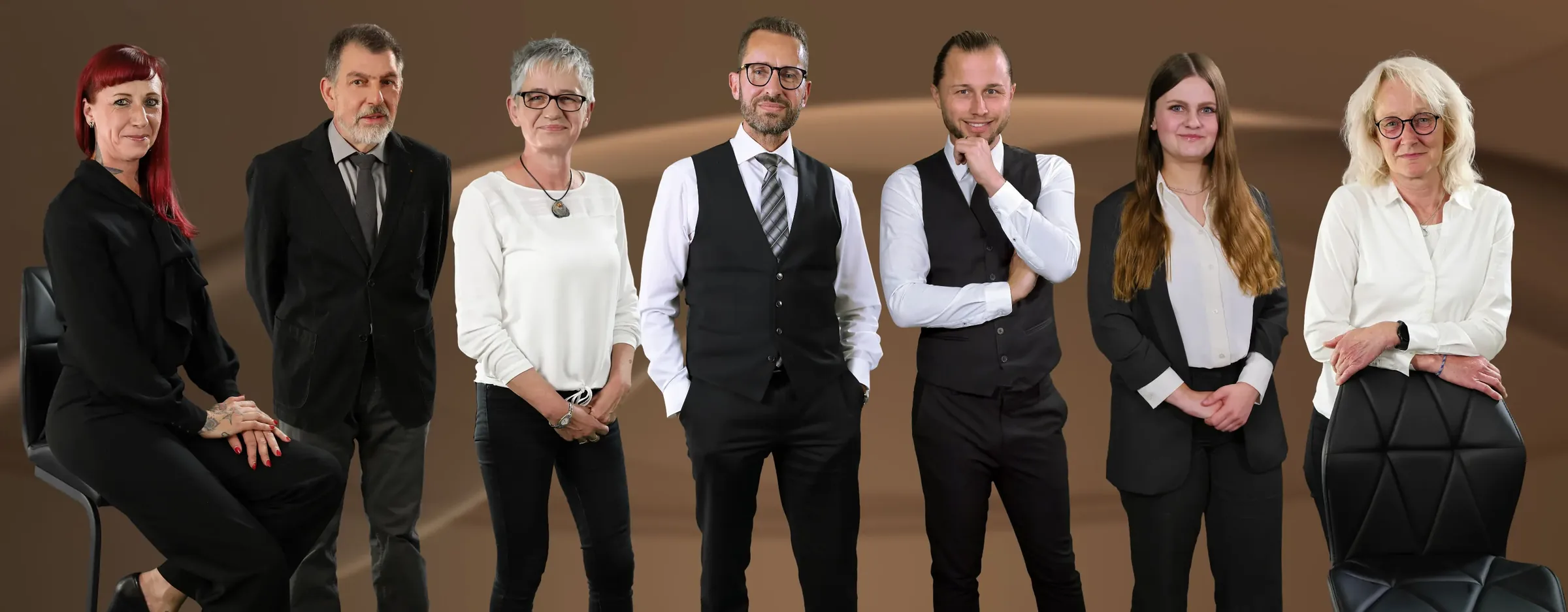 Das Team von Bestattungen Schwarz: sieben Menschen vor einem braunen Hintergrund