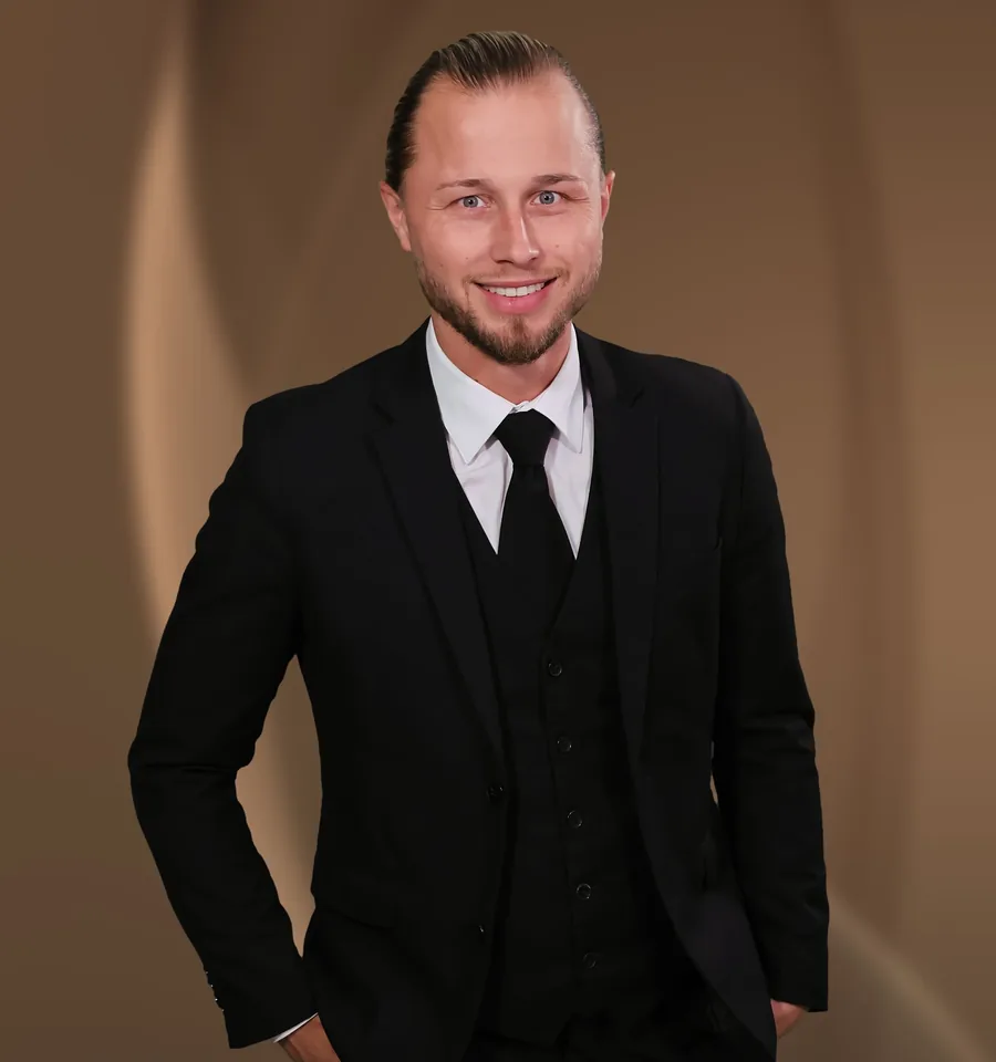 Kevin Klepping, ein junger Mann mit schwarzer Weste und Krawatte, steht mit den Händen in den Taschen