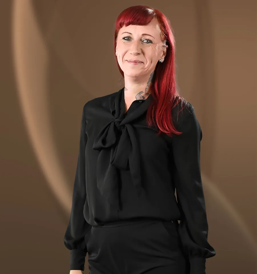Wiebke Artmann, eine Frau mit roten Haaren in schwarzer Bluse und schwarzer Hose