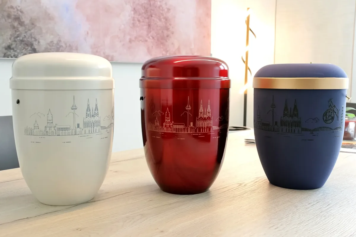 Weiße, rote und blaue Urne mit Darstellungen der Kölner Skyline in der Urnenausstellung